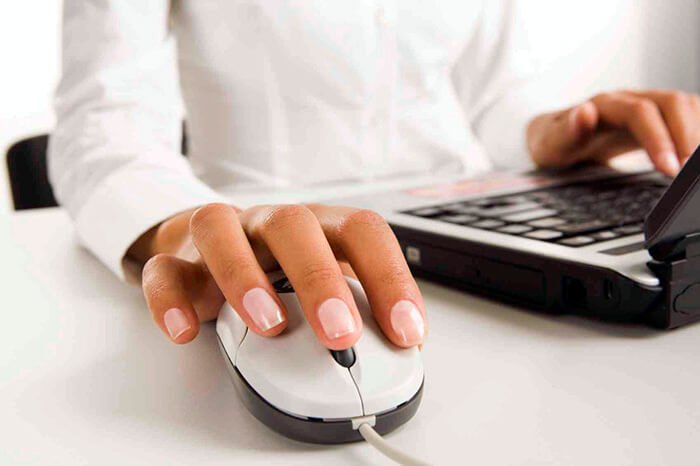 Womanís hands touching computer mouse and keys of black opened laptop
